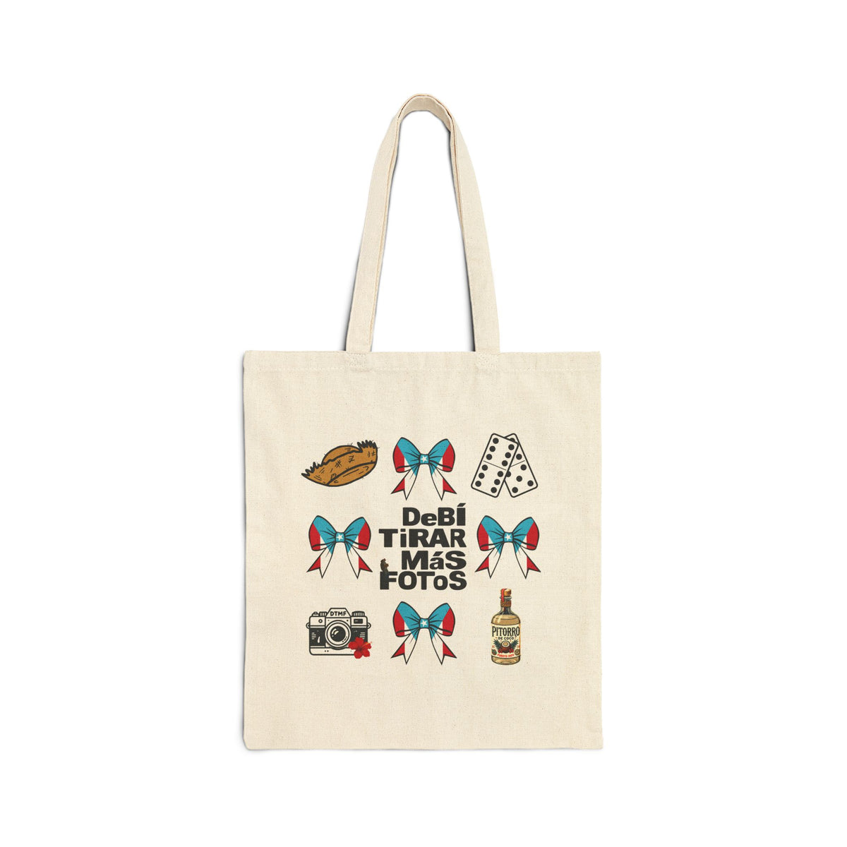 An off-white canvas tote bag with long handles, featuring a graphic print of various icons (a hot dog, dice, camera, bottle) and the Spanish text 'DeBÍ TIRAR MÁS FOTOS' in black.