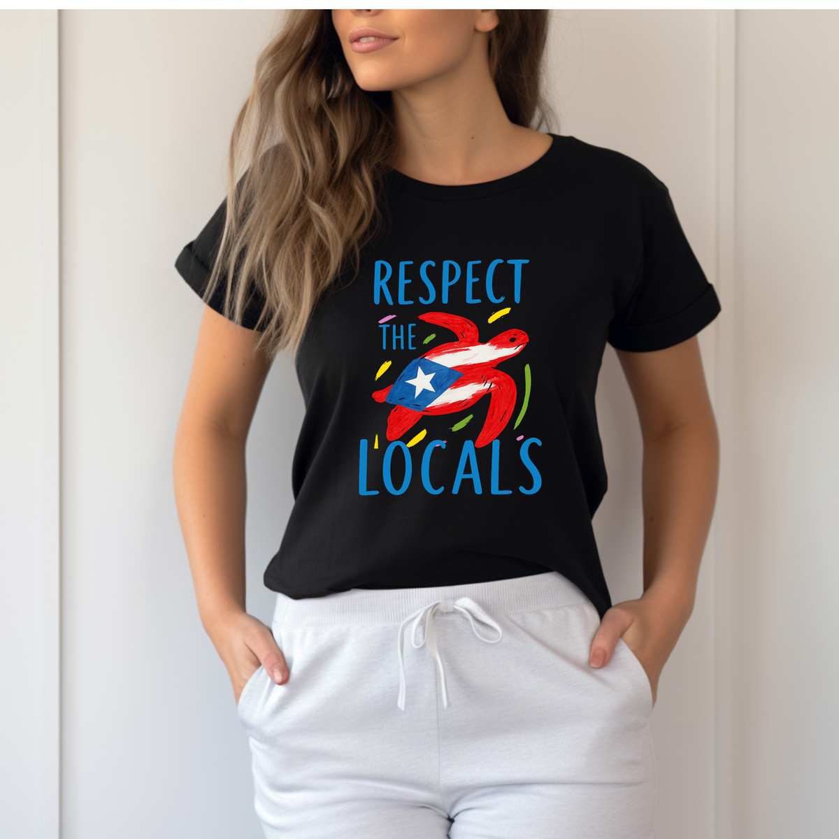 Person wearing a black t-shirt with colorful graphic and text 'RESPECT THE LOCALS' on a plain background