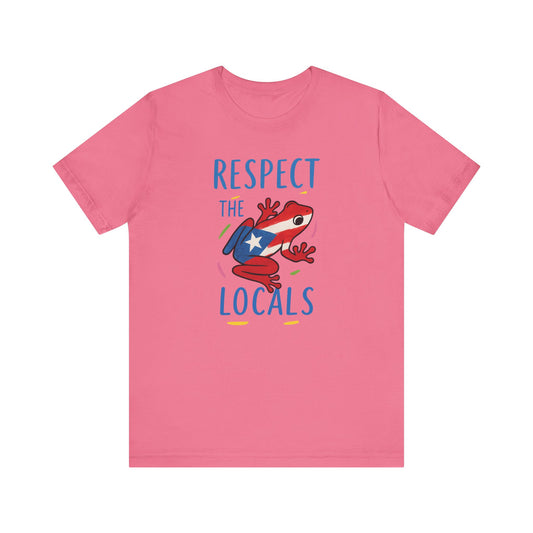 A pink short-sleeve crewneck t-shirt featuring a graphic of a red and white frog wearing a blue backpack with a white star, surrounded by the text 'RESPECT THE LOCALS' in blue, on a solid white background.